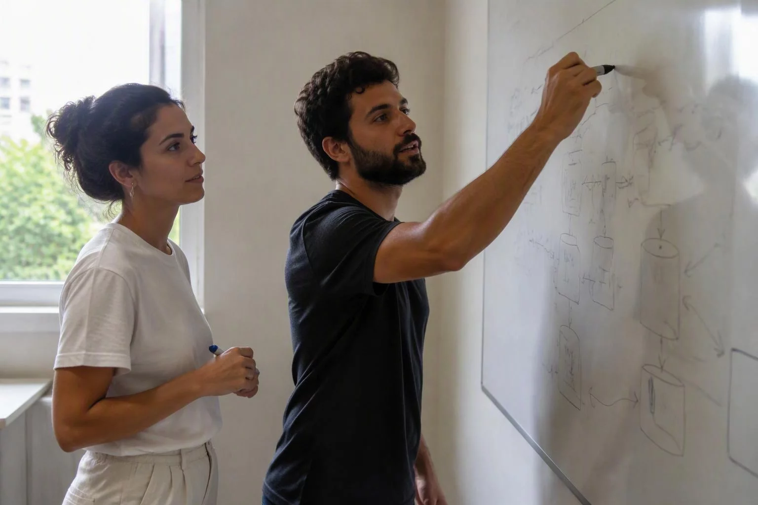 Duas pessoas diante do quadro branco com os sistemas ligados por setas